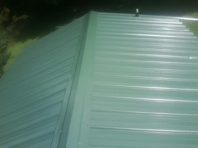 New green metal panels meeting at the ridge of a roof — Flat Roof Repair work by our crew in Fernandina Beach