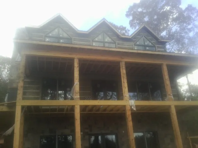 Dormers and porch framing on a large log home under construction — Roof Coating work by our crew in Fernandina Beach