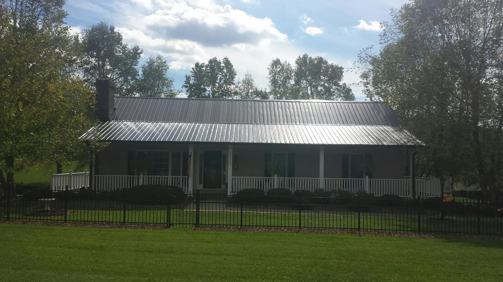 Gray metal roof on a brick ranch with a full width front porch — Gutter Guard Installation work by our crew in Fernandina Beach