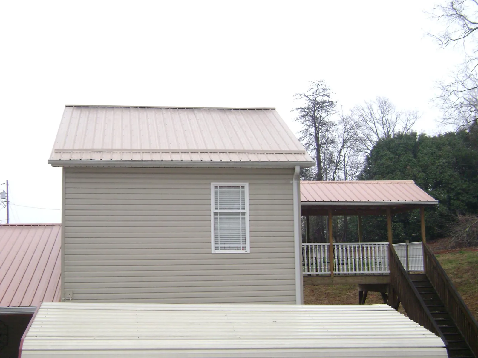 Tan metal roofs on a two story addition and attached porch, from a Roof Replacement job in Fernandina Beach